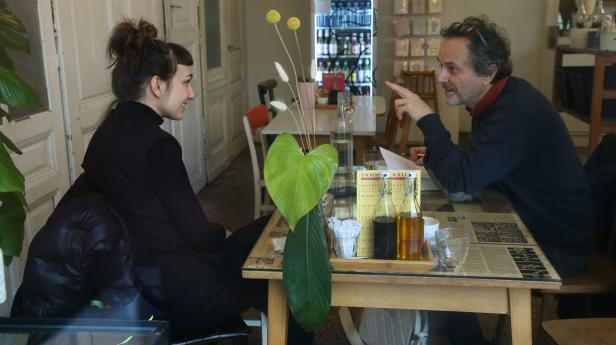 In einem Café sitzen ein Mann und eine Frau an einem Tisch und unterhalten sich.
