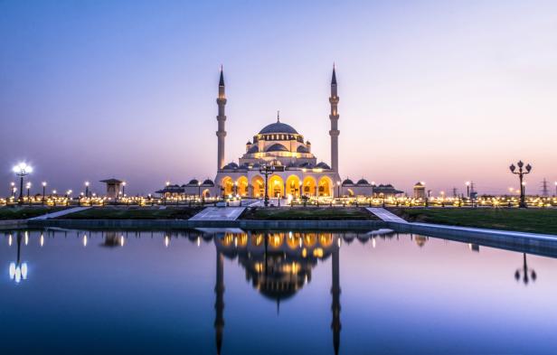 Die Al-Noor-Moschee in Sharjah spiegelt sich im Wasser bei Dämmerung.