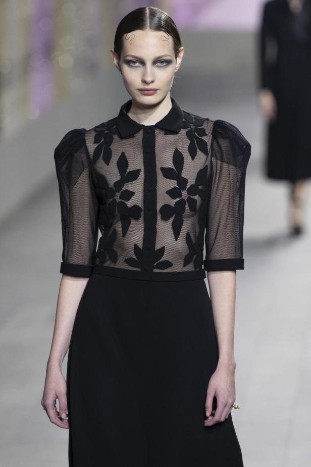 Ein Model präsentiert ein schwarzes Kleid mit transparentem Oberteil von Christian Dior.