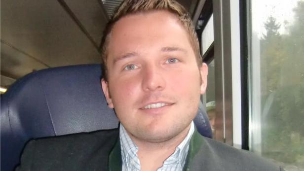 Ein Mann in Trachtenjacke sitzt in einem Zug.