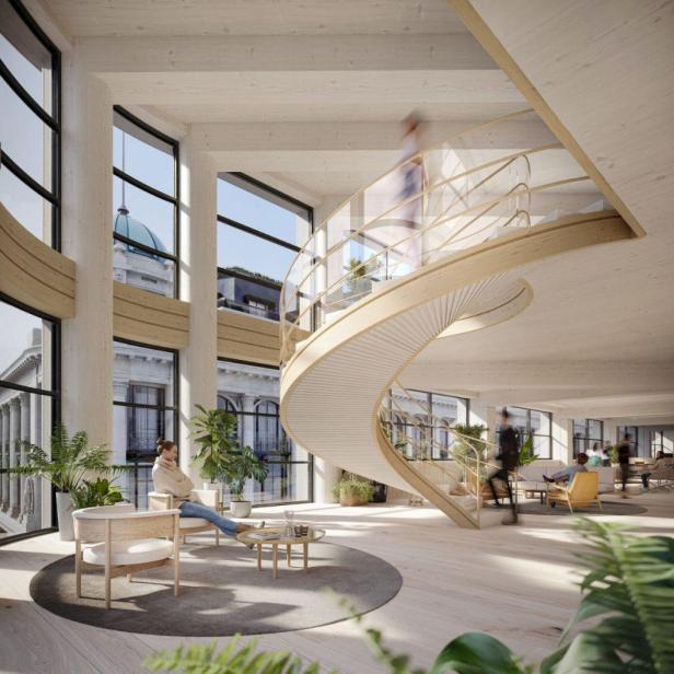 Eine Frau sitzt in einem hellen Büro mit einer Wendeltreppe.