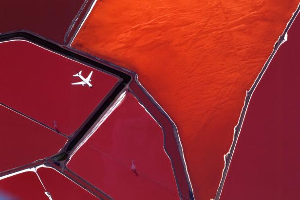 Ein Flugzeug überfliegt rote Salzbecken.