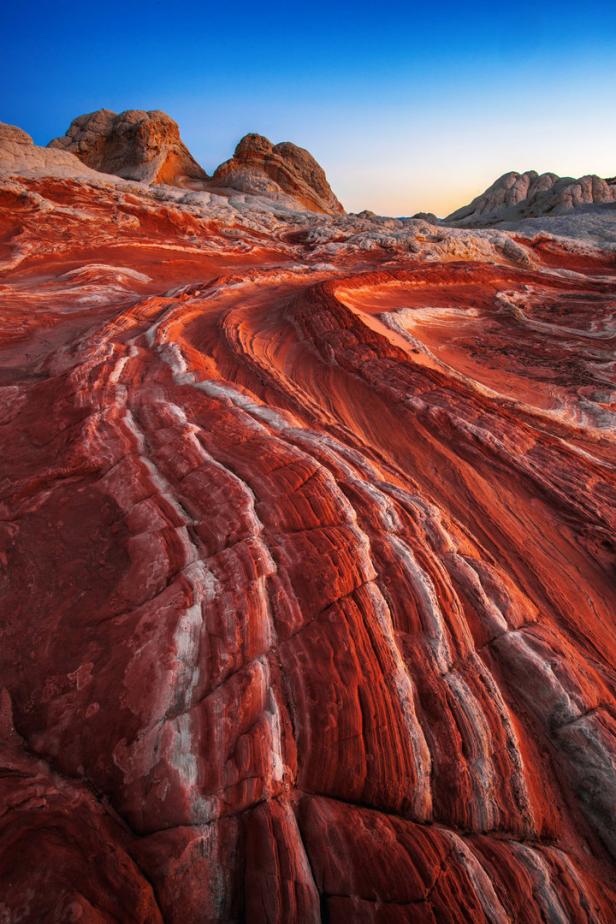 Die rötlichen Felsformationen von White Pocket in Arizona unter blauem Himmel.