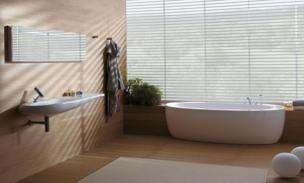 Ein modernes Badezimmer mit Badewanne, Waschbecken und Jalousien vor dem Fenster.
