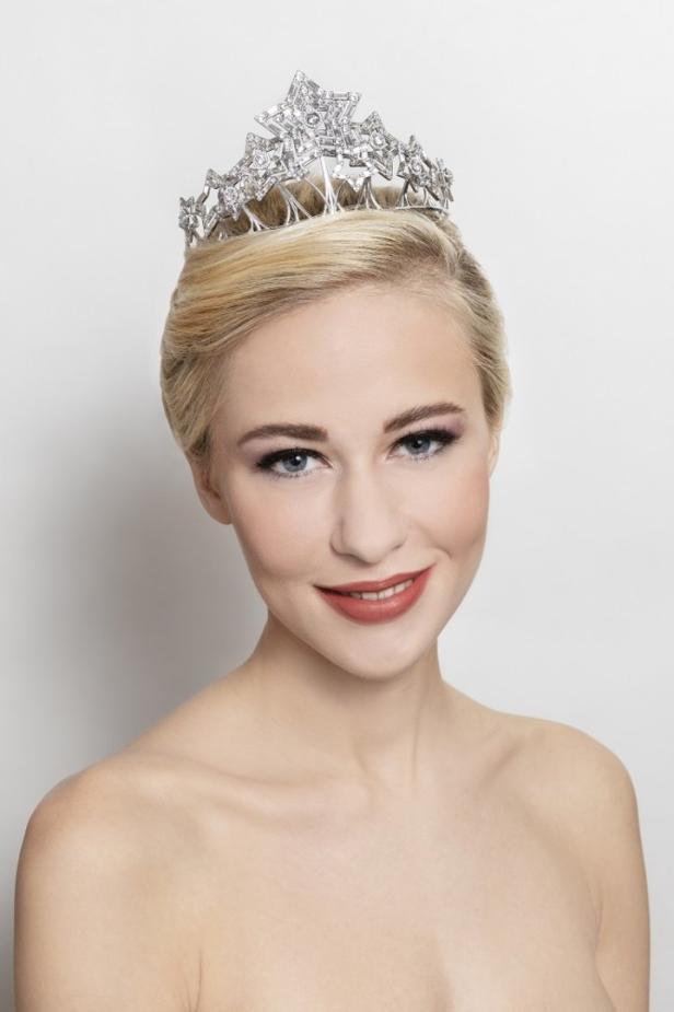 Eine blonde Frau mit einer silbernen Krone lächelt.