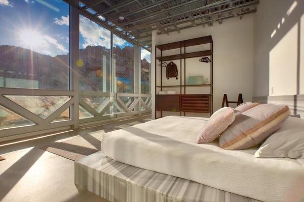Ein Schlafzimmer mit großem Fenster und Blick auf eine Berglandschaft.