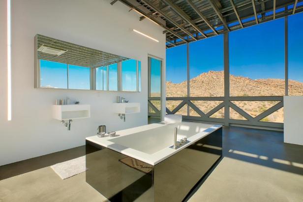 Ein modernes Badezimmer mit freistehender Badewanne und Blick auf eine Wüstenlandschaft.