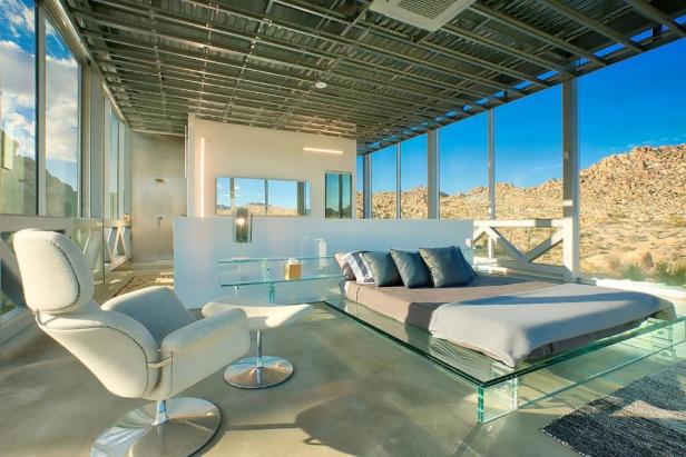 Ein modernes Schlafzimmer mit Glaswänden und Blick auf eine Wüstenlandschaft.