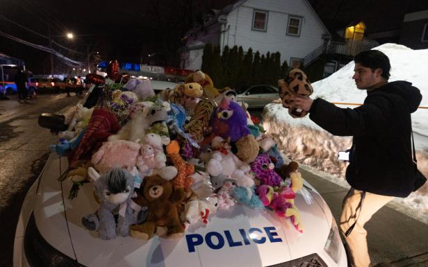 Ein Mann legt Stofftiere auf die Motorhaube eines Polizeiautos als Denkmal.