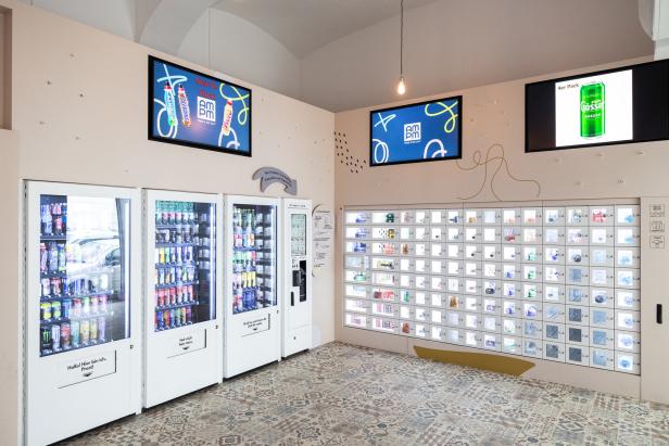 Ein Raum mit Getränke- und Snackautomaten und Bildschirmen mit Werbung.