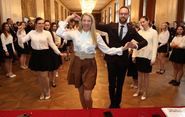 Eine Gruppe junger Leute tanzt in einem festlichen Saal.