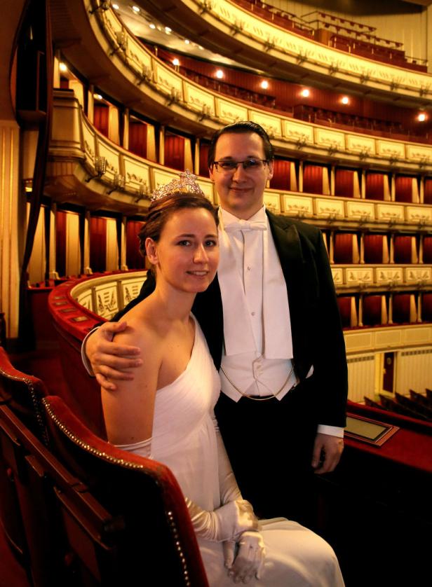 Ein Paar in Abendgarderobe posiert in einem Opernhaus.