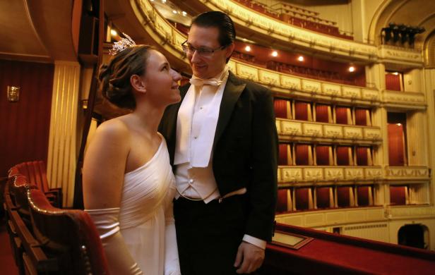 Ein Paar in Abendgarderobe steht in einem Opernhaus und schaut sich an.