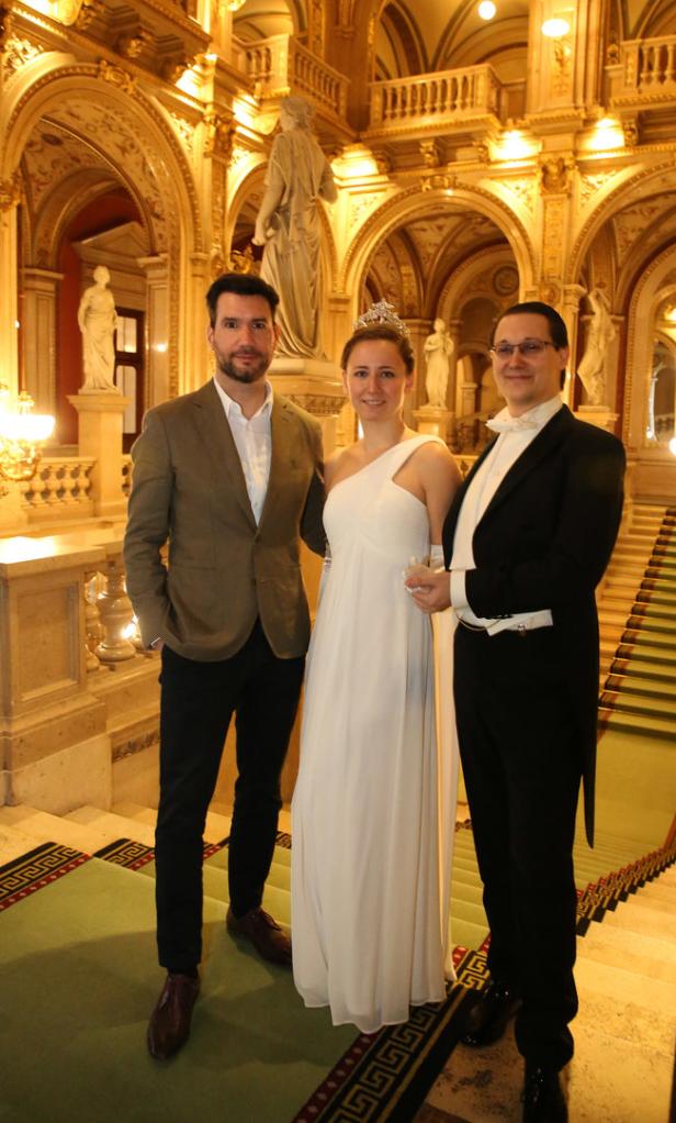 Drei Personen posieren auf einer Treppe in der Wiener Staatsoper.
