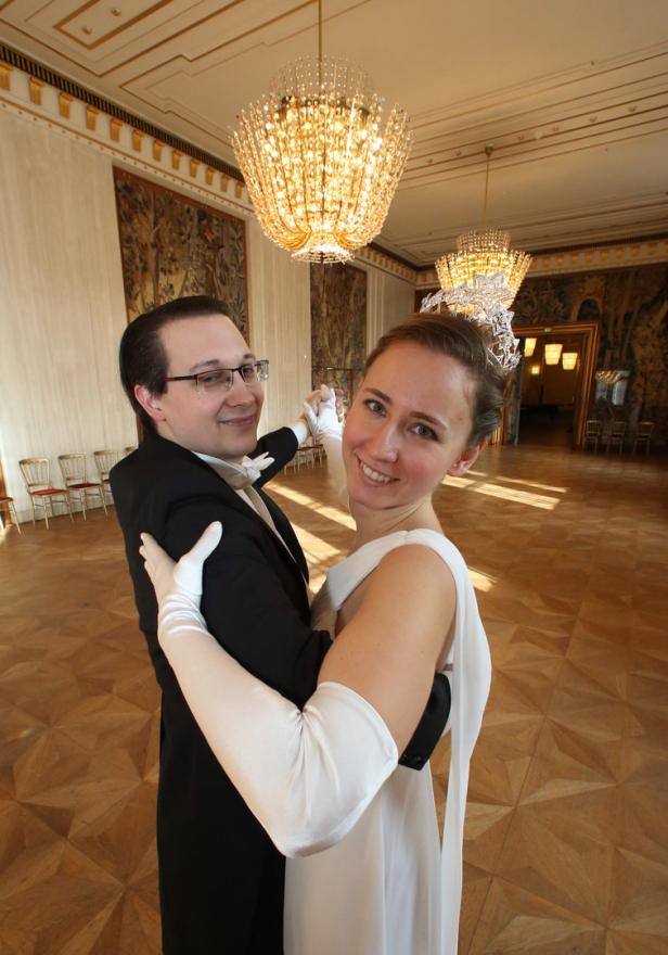 Ein Paar tanzt in einem Ballsaal unter funkelnden Kronleuchtern.