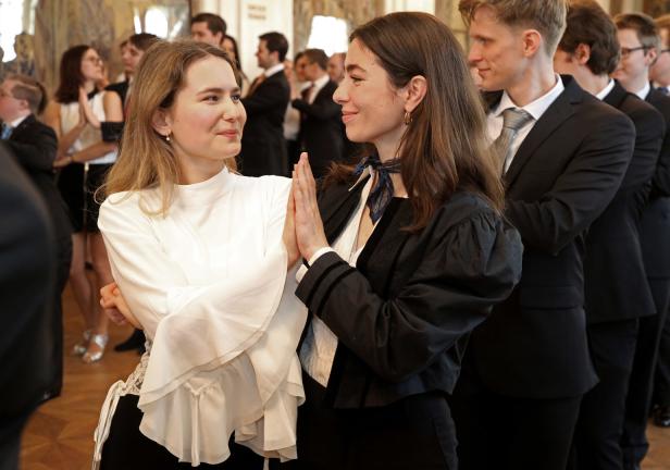 Zwei junge Frauen stehen sich gegenüber und berühren ihre Hände.