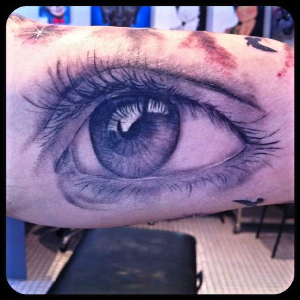 Ein Tattoo zeigt ein detailliertes, realistisch wirkendes Auge auf einem Arm.