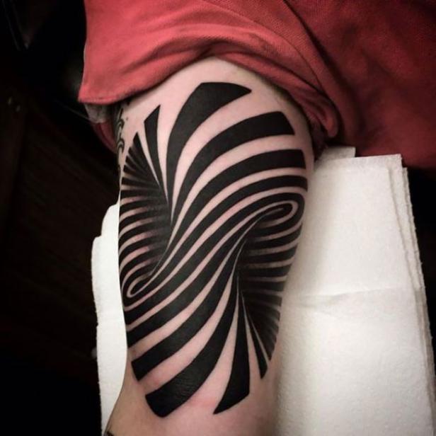 Ein Tattoo auf einem Arm zeigt ein spiralförmiges, schwarzes und weißes Muster.