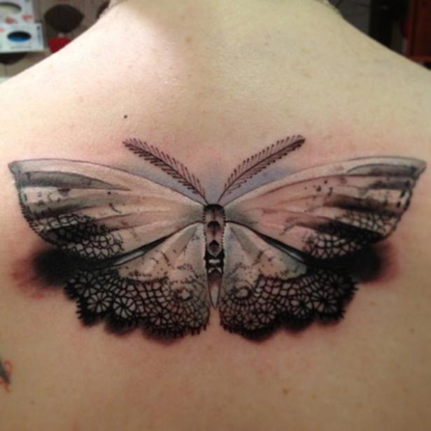 Ein Tattoo auf dem Rücken zeigt einen Schmetterling mit Spitzenmuster.