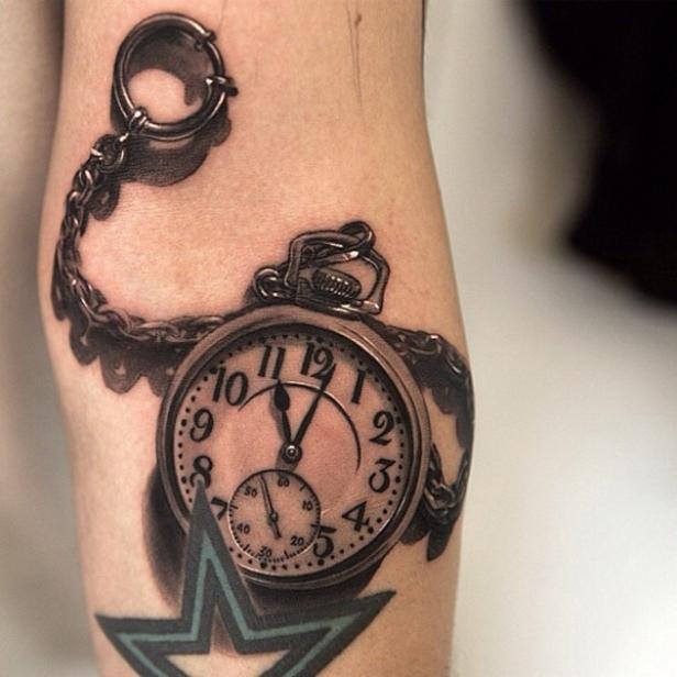 Ein Tattoo auf einem Bein zeigt eine Taschenuhr mit Kette und einen Stern.