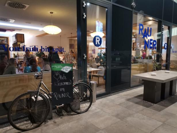 Ein Fahrrad steht vor dem Restaurant Rauner, das mit „Von früh bis spät“ wirbt.