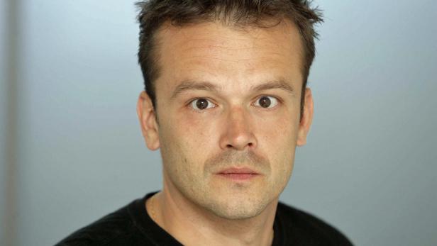 Porträt eines Mannes mit braunen Augen und kurzem, dunklem Haar.