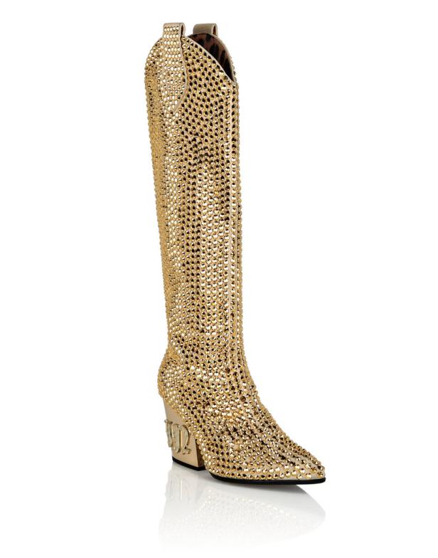 Ein goldener, kniehoher Stiefel, der vollständig mit Strasssteinen besetzt ist.