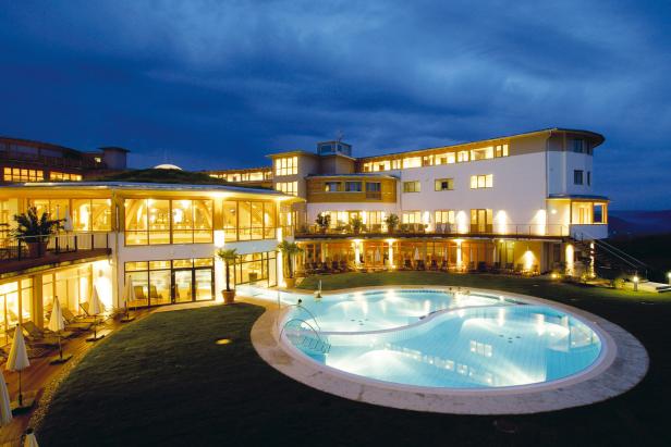 Ein großes Hotel mit einem beleuchteten Pool bei Nacht.