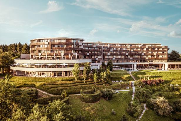 Ein großes Hotelgebäude mit einem gepflegten Garten im Grünen.