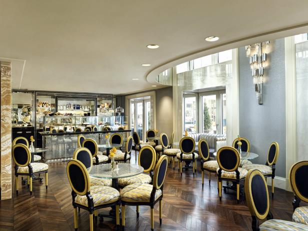 Ein elegantes Café mit Tischen und Stühlen vor einer Theke mit Gebäck.