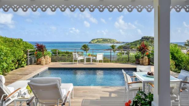Ein Swimmingpool mit Meerblick von einer Terrasse aus.