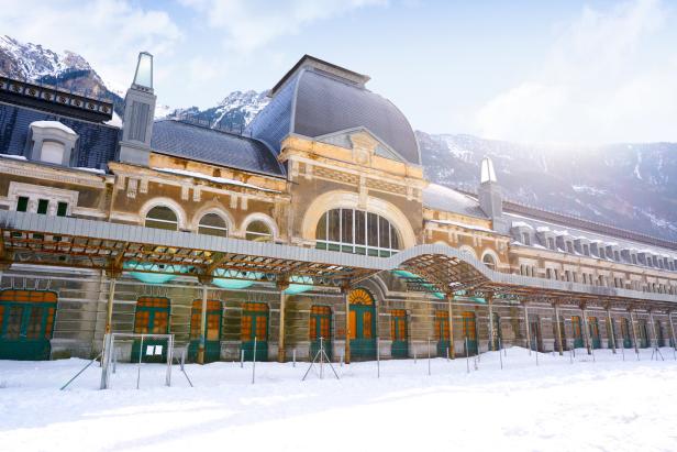 Das historische Bahnhofsgebäude von Canfranc im Winter mit schneebedeckten Bergen im Hintergrund.