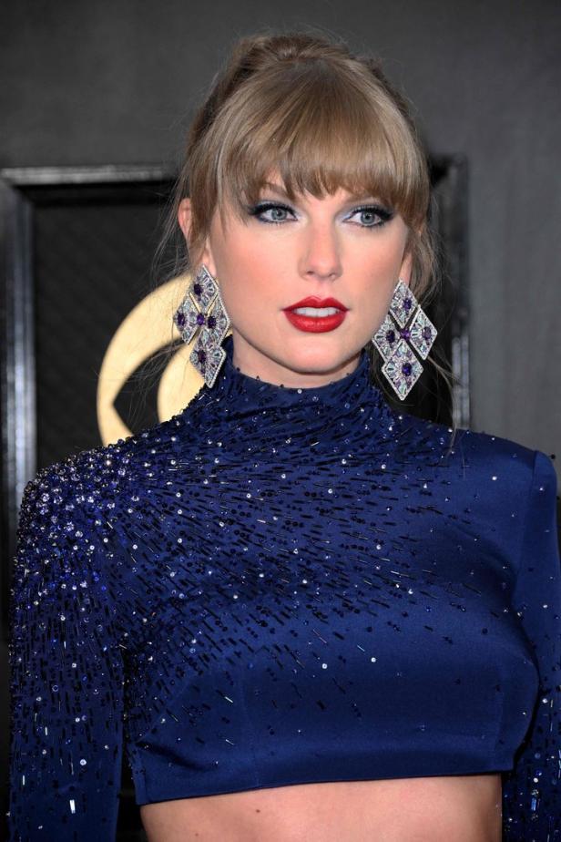 Taylor Swift trägt ein blaues, paillettenbesetztes Kleid und auffällige Ohrringe.