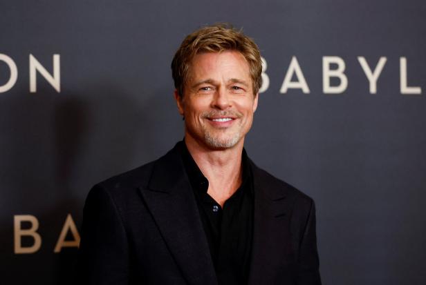 Brad Pitt posiert vor einer Wand mit dem Schriftzug „Babylon“.