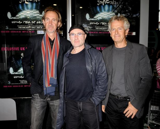 Die Bandmitglieder von Genesis posieren vor einem Filmplakat.
