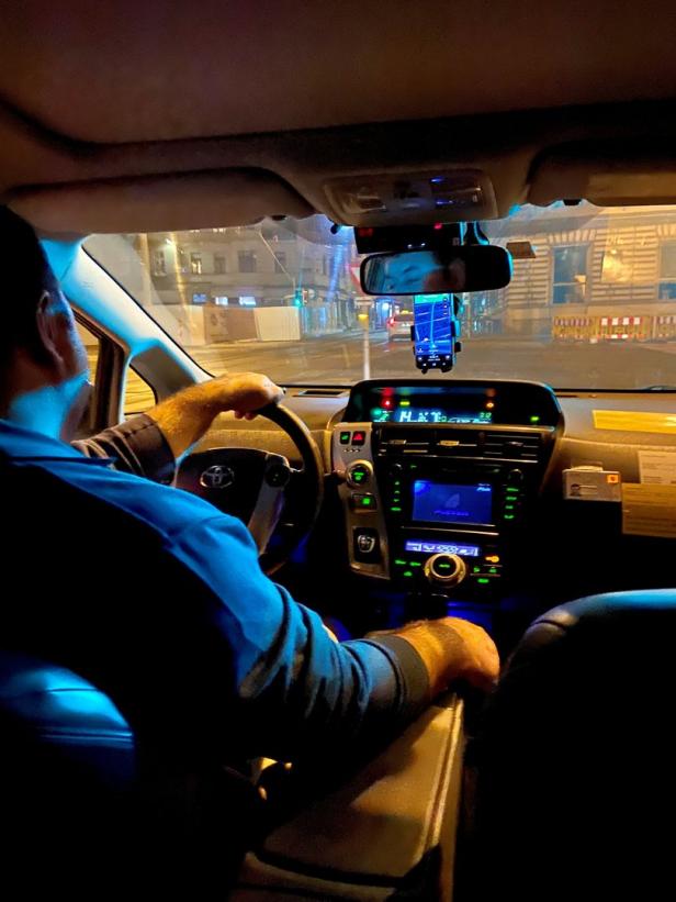 Ein Taxifahrer fährt nachts durch die Stadt.