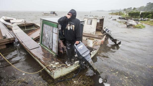 Ein Mann steht in einem überfluteten Boot während eines Sturms.