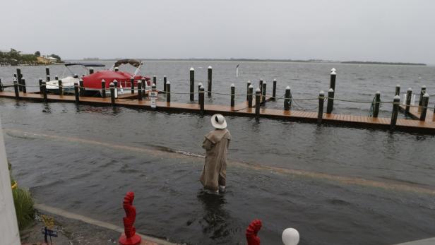 Eine Person steht im überfluteten Wasser in der Nähe eines Bootsstegs.