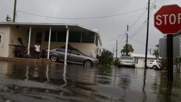 Eine überflutete Wohngegend mit Autos und einem Stoppschild im Vordergrund.