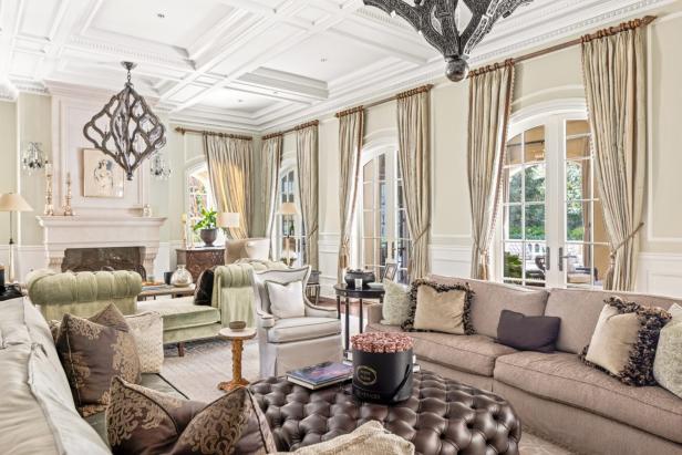 Ein luxuriöses Wohnzimmer mit eleganten Möbeln und einem großen, ledernen Ottoman im Vordergrund.