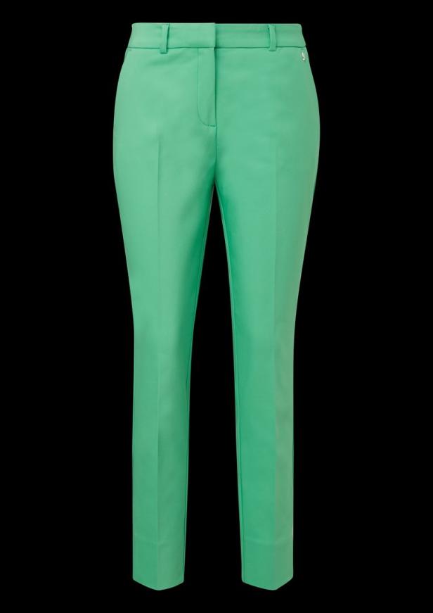 Eine hellgrüne Stoffhose vor einem schwarzen Hintergrund.
