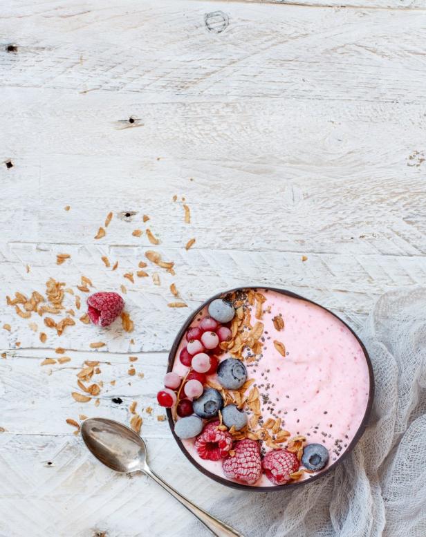 Eine Schüssel mit rosa Smoothie, garniert mit Beeren, Müsli und Chiasamen.