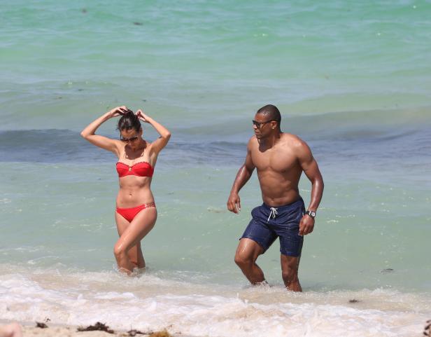 Ein Paar steht im seichten Wasser an einem sonnigen Strand.