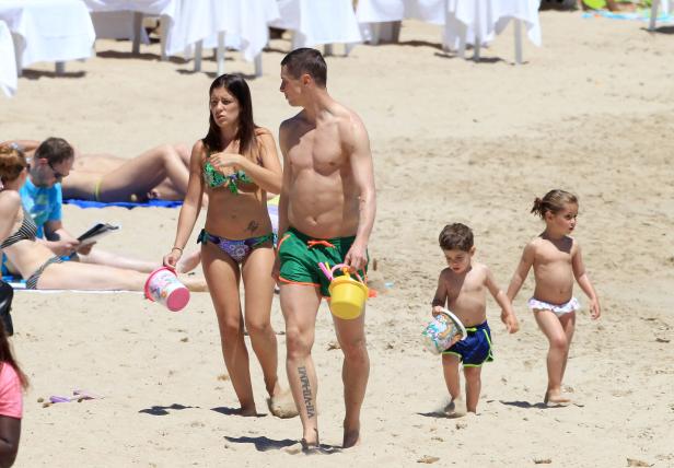 Eine Familie mit zwei kleinen Kindern geht am Strand spazieren.