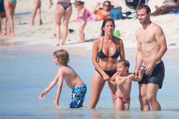 Eine Familie watet im flachen Wasser an einem sonnigen Strand.