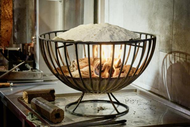 Ein Fladenbrot liegt auf einem Korb mit glühenden Kohlen.