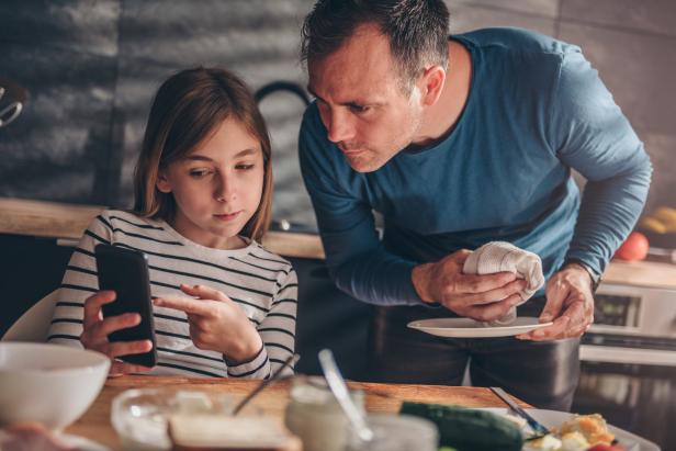 Eine Tochter zeigt ihrem Vater, was sie sich am Smartphone ansieht.