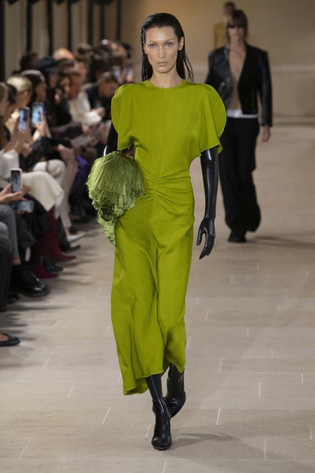 Bella Hadid präsentiert ein grünes Kleid und schwarze Handschuhe auf dem Laufsteg.