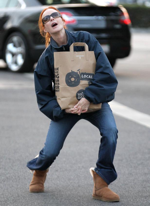 Eine Frau mit Sonnenbrille trägt eine Einkaufstasche von Whole Foods.