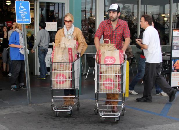 Ein Mann und eine Frau schieben Einkaufswagen voller Tüten von Whole Foods.